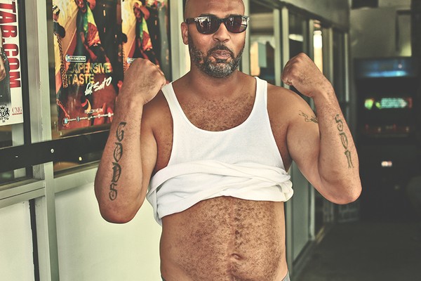 "Bone" shows us where he was shot in his abdomen and his tattoos. He has been shot multiple times on different occasions and has survived. His tattoos read: "Gods Son." 